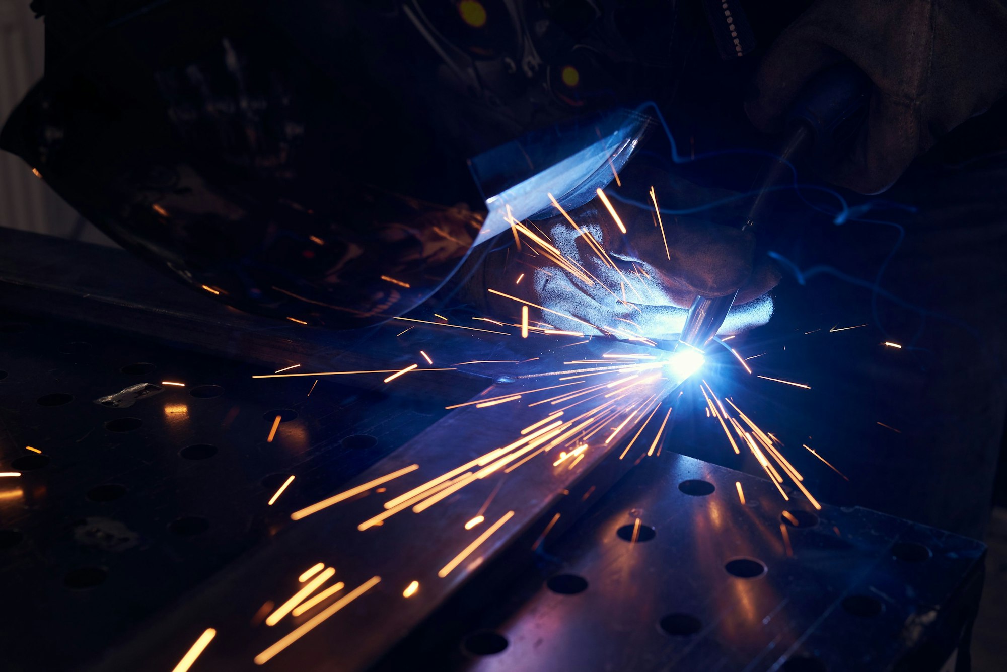 worker with protective mask welding metal closeup